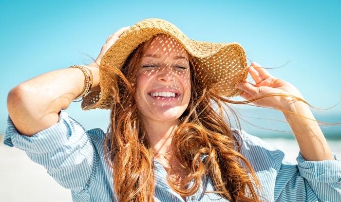 Mujer con sombrero sonriendo en la playa