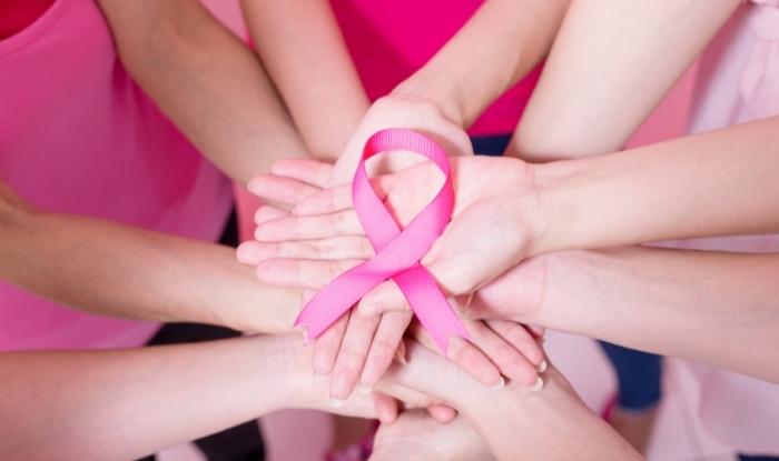 Test de cáncer de mama. Mujeres con manos enlazadas mostrando el lazo rosado de la lucha contra el cáncer. 