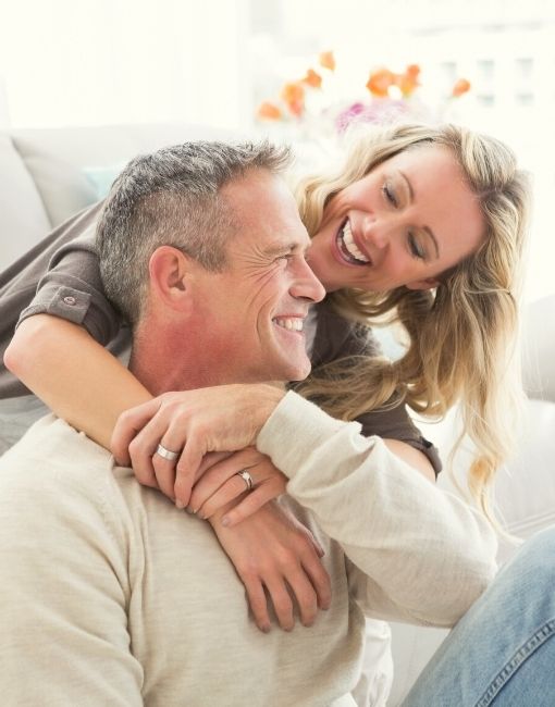Mujer abrazando a hombre y ambos sonriendo. Terapia de reemplazo hormonal para hombres.