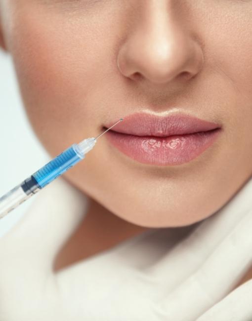 Jeringa en labios de mujer para tratamiento de aumento de labios