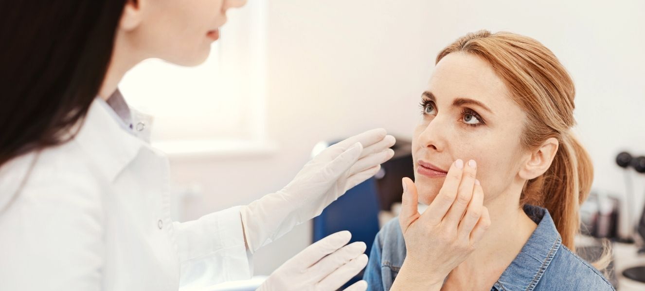 Doctora tocando cara de una paciente mujer<br />
sobre procedimiento bichectomia