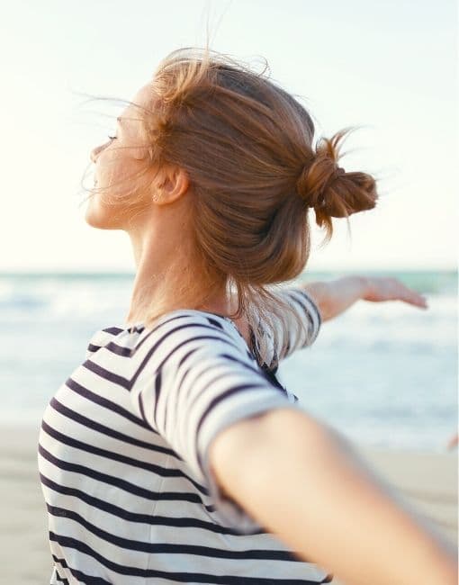 Mujer feliz en la playa con brazos abiertos